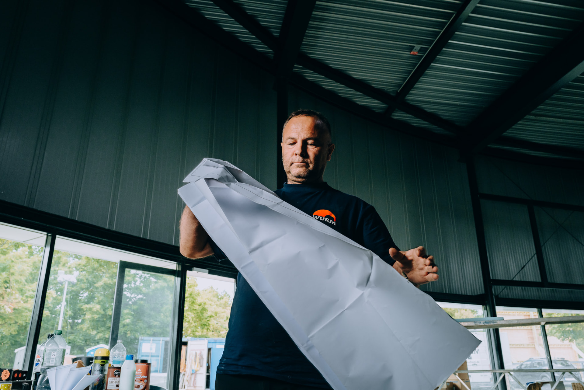 Monteur der Wurm GmbH faltet einen Plan in der Bauhalle