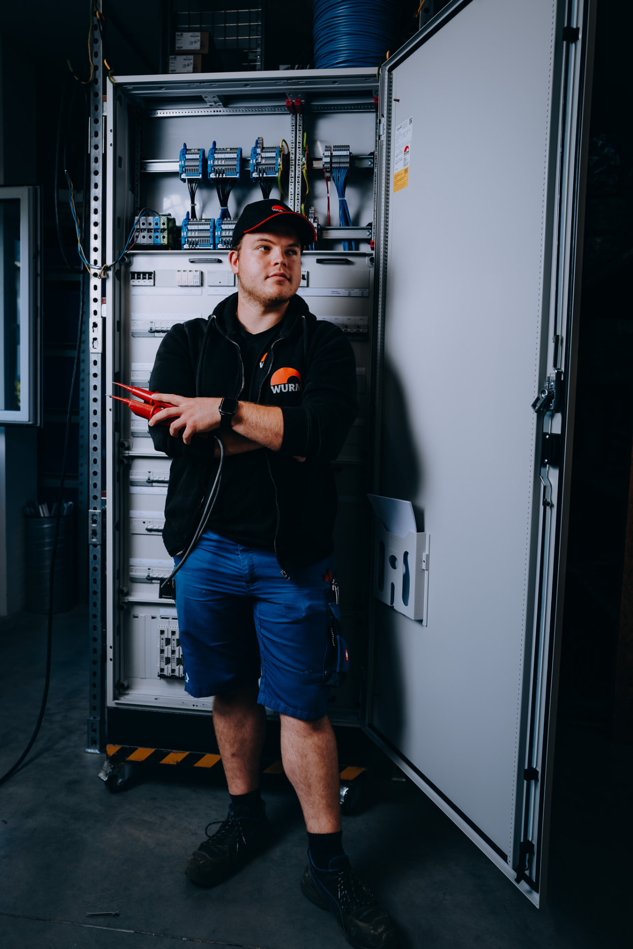 Elektroniker vor geöffnetem Schaltschrank in der Fertigung