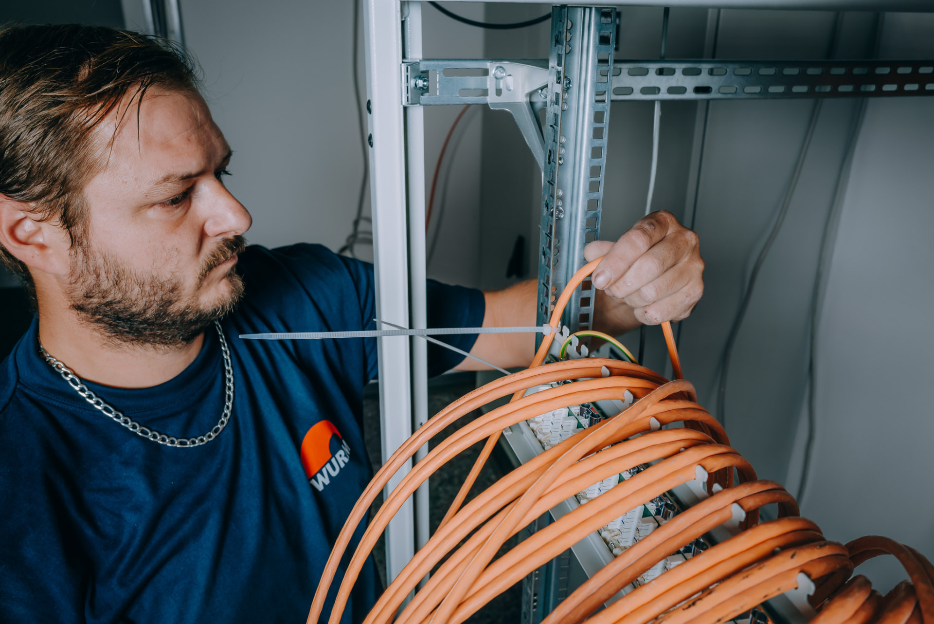 Elektroniker der Wurm GmbH fixiert Datenleitungen am Verteilerrahmen