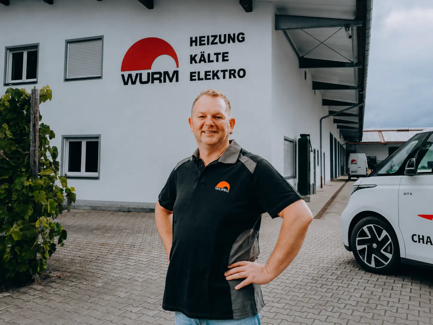 Portrait eines Monteurs in Wurm-Arbeitskleidung vor dem Betrieb