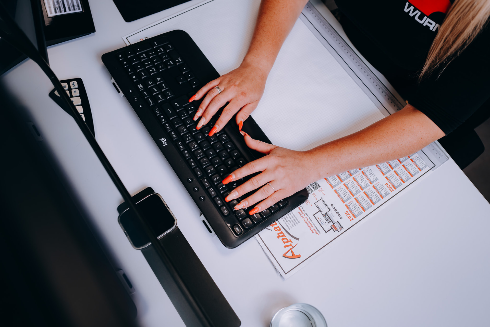 Arbeitsplatz im Innendienst mit Tastatur, Plänen und Kalender