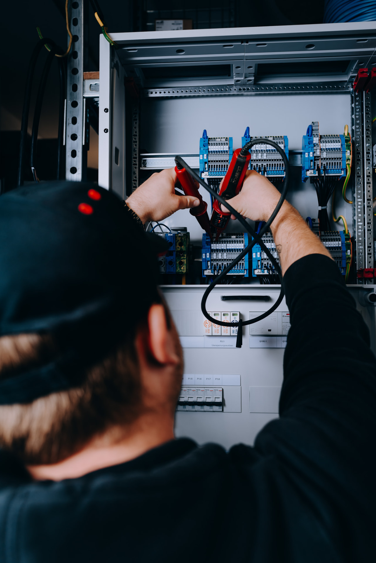 Elektroniker prüft Spannung im offenen Schaltschrank