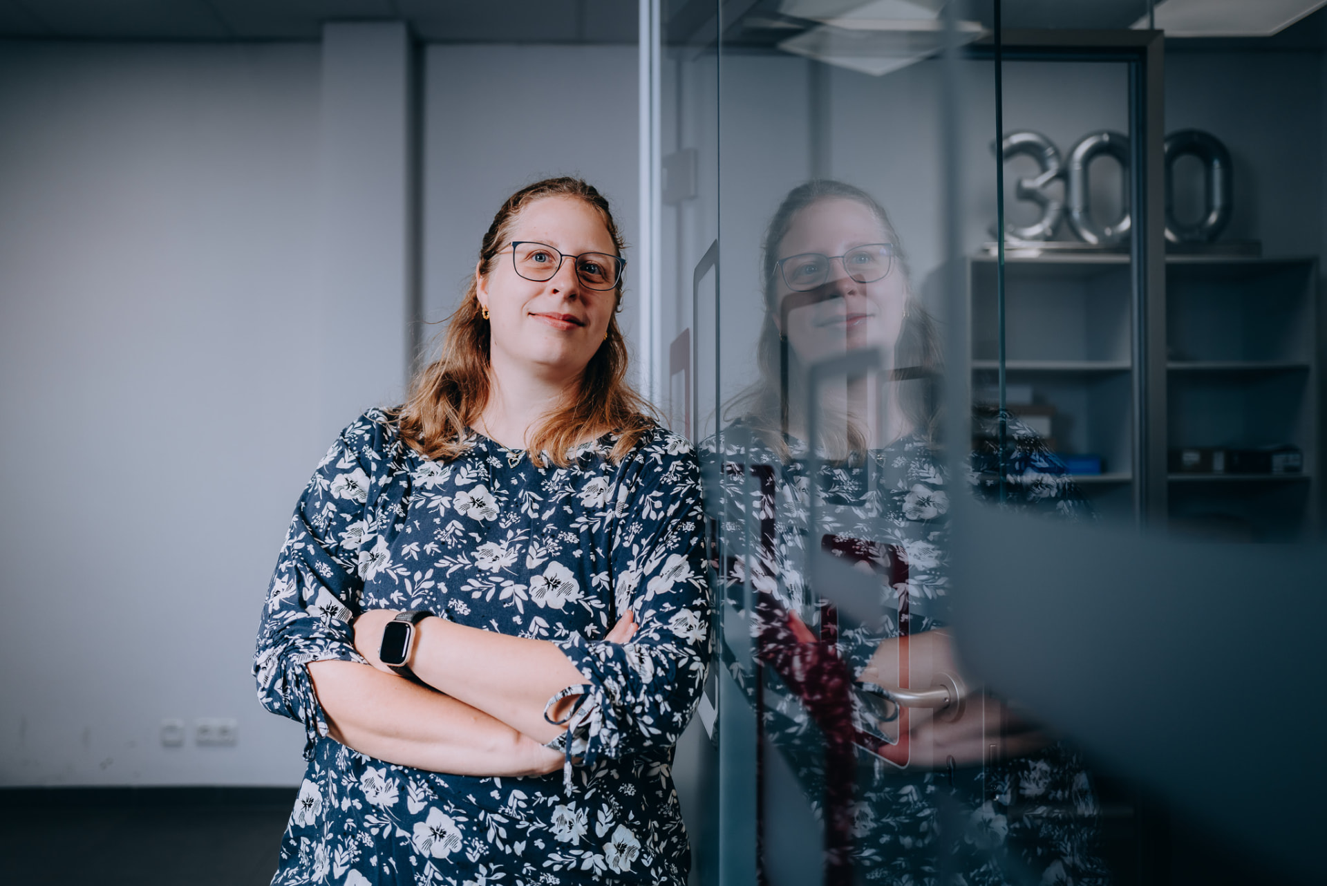 Portrait einer Mitarbeiterin mit Spiegelung in der Glastür