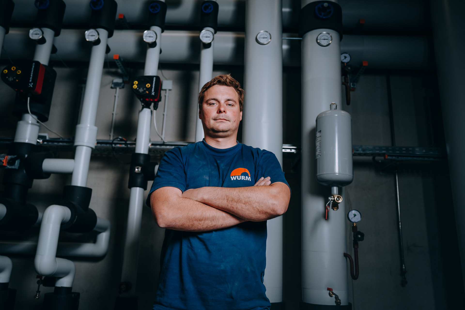 Anlagenmechaniker vor Heizungsverteilung mit Manometern