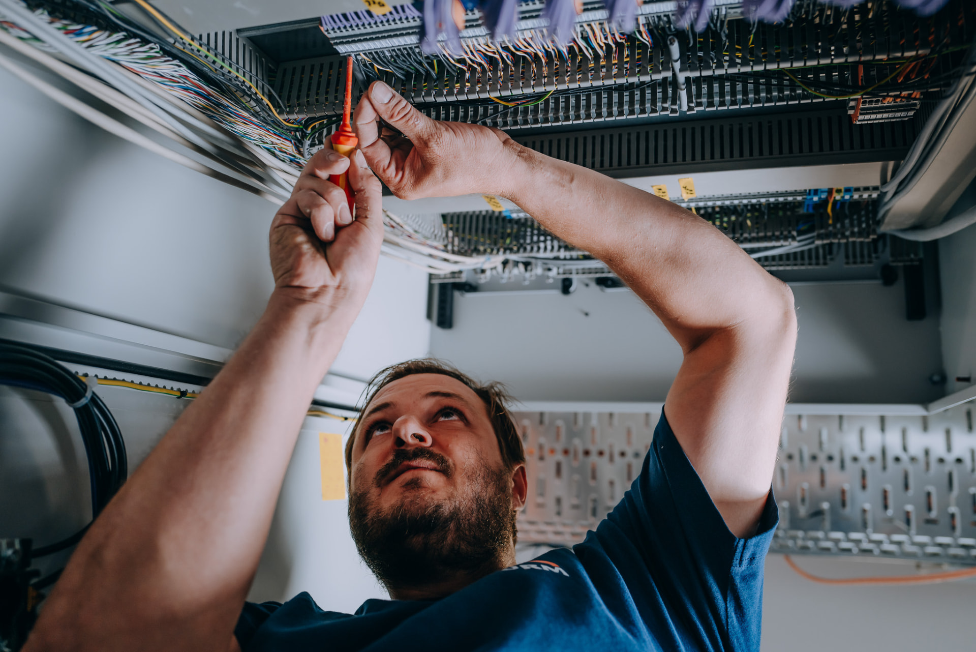 Elektroniker prüft die Verdrahtung im Schaltschrank von unten