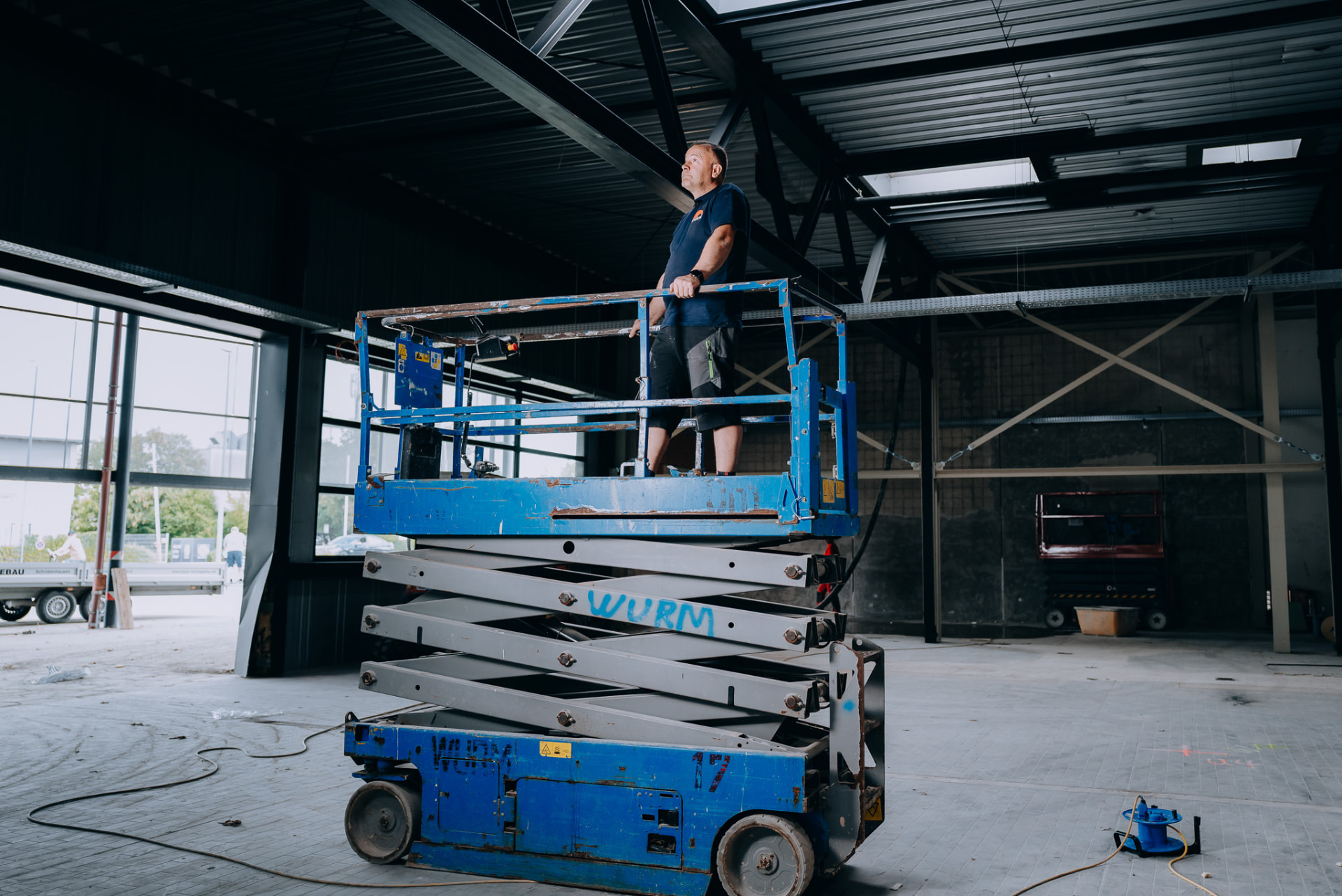 Monteur der Wurm GmbH auf einer Scherenarbeitsbühne in einer Gewerbehalle
