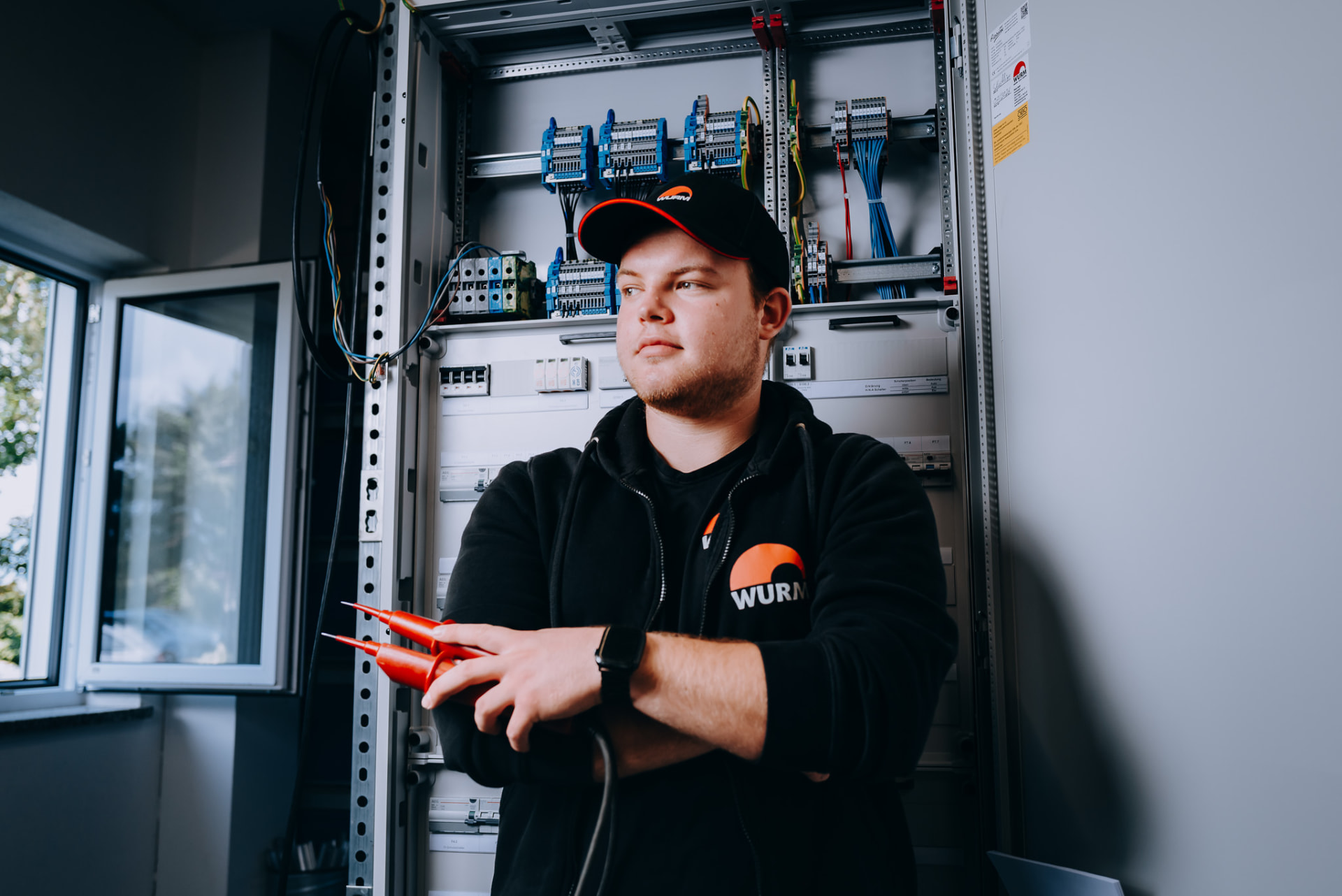 Portrait: Elektroniker vor verdrahteter Schaltanlage