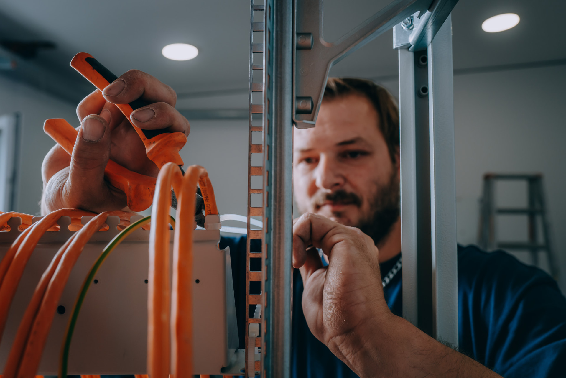 Elektroniker konfektioniert Datenleitungen im Netzwerkverteiler