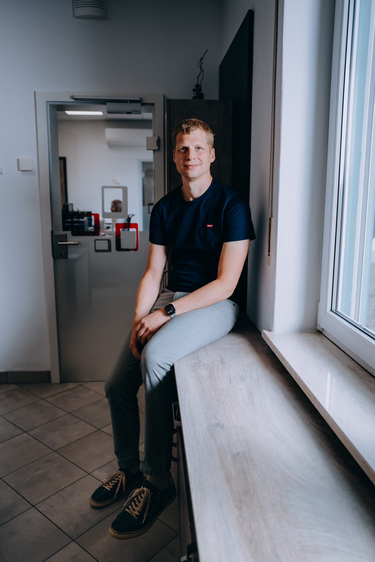Portrait eines Mitarbeiters an der Fensterbank im Büro