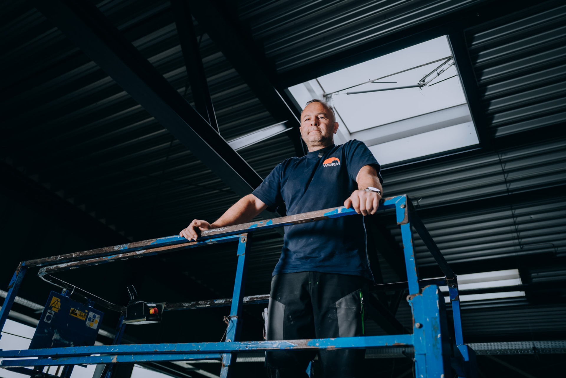 Monteur der Wurm GmbH auf der Arbeitsbühne im Gegenlicht des Lichtbands