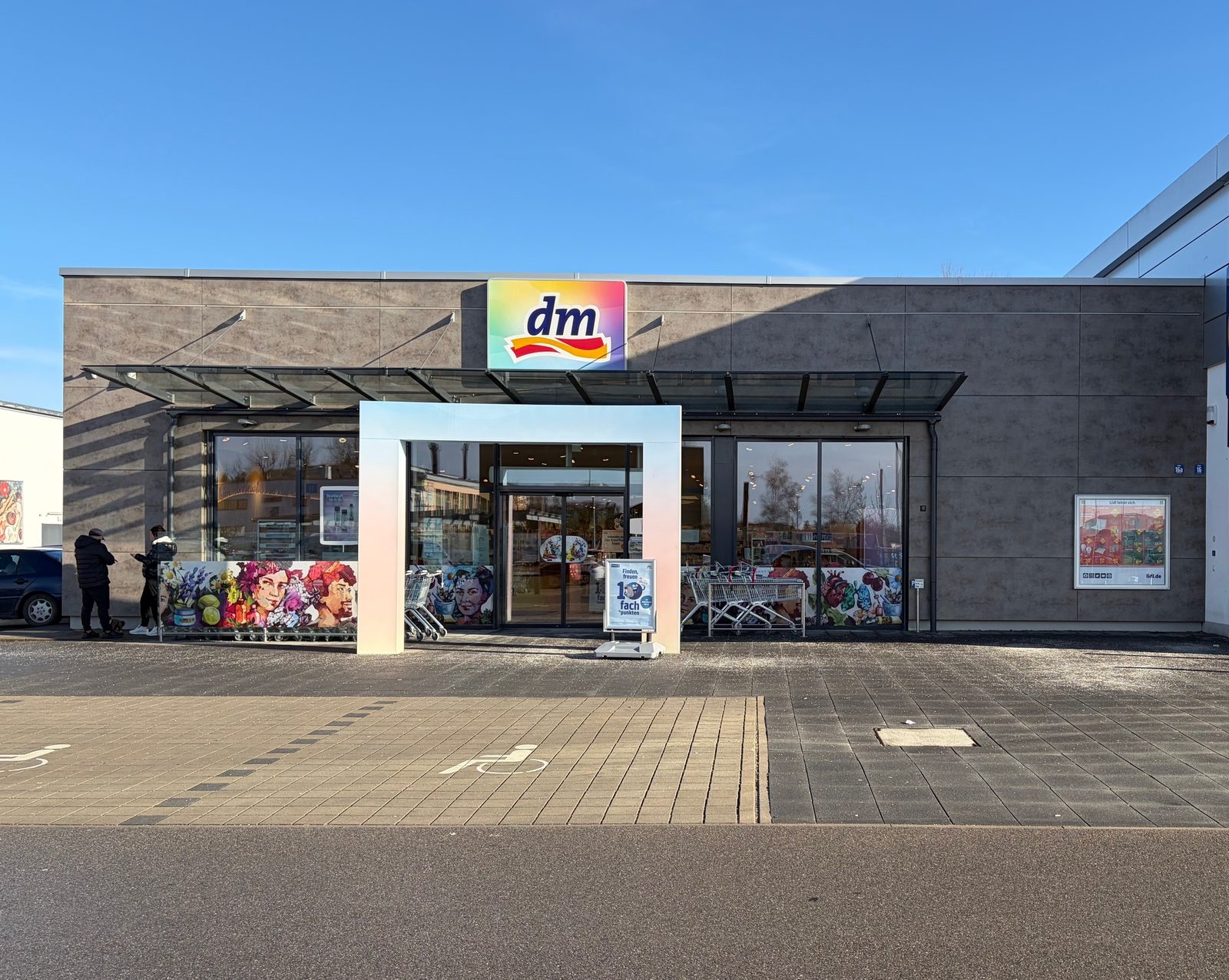 Außenansicht des neu gebauten dm-Drogeriemarkts in Penzberg mit Eingangsbereich und Parkplatz.