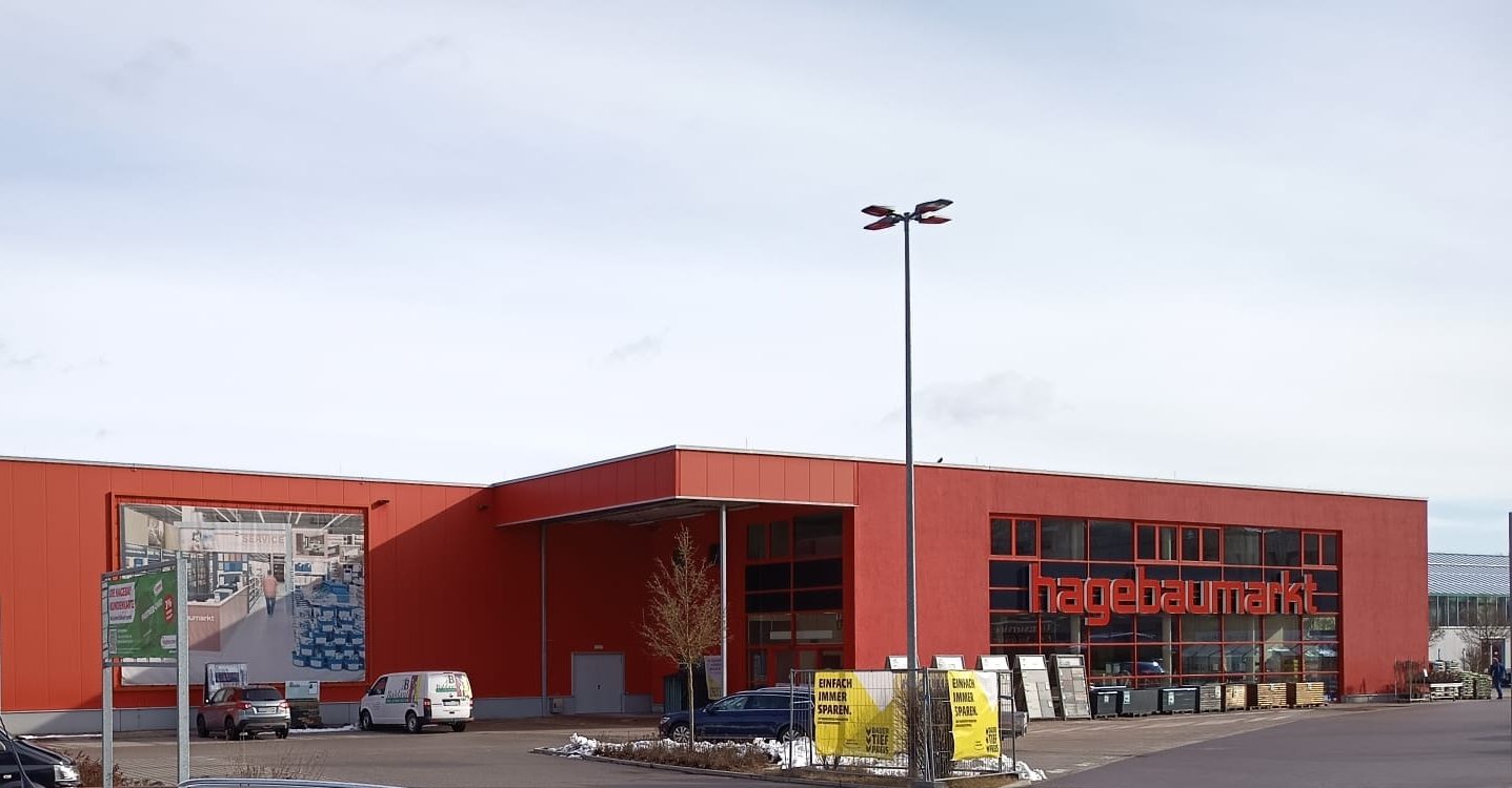Außenansicht des neu gebauten Hagebaumarkts in Kelheim mit roter Fassade und Parkplatz.