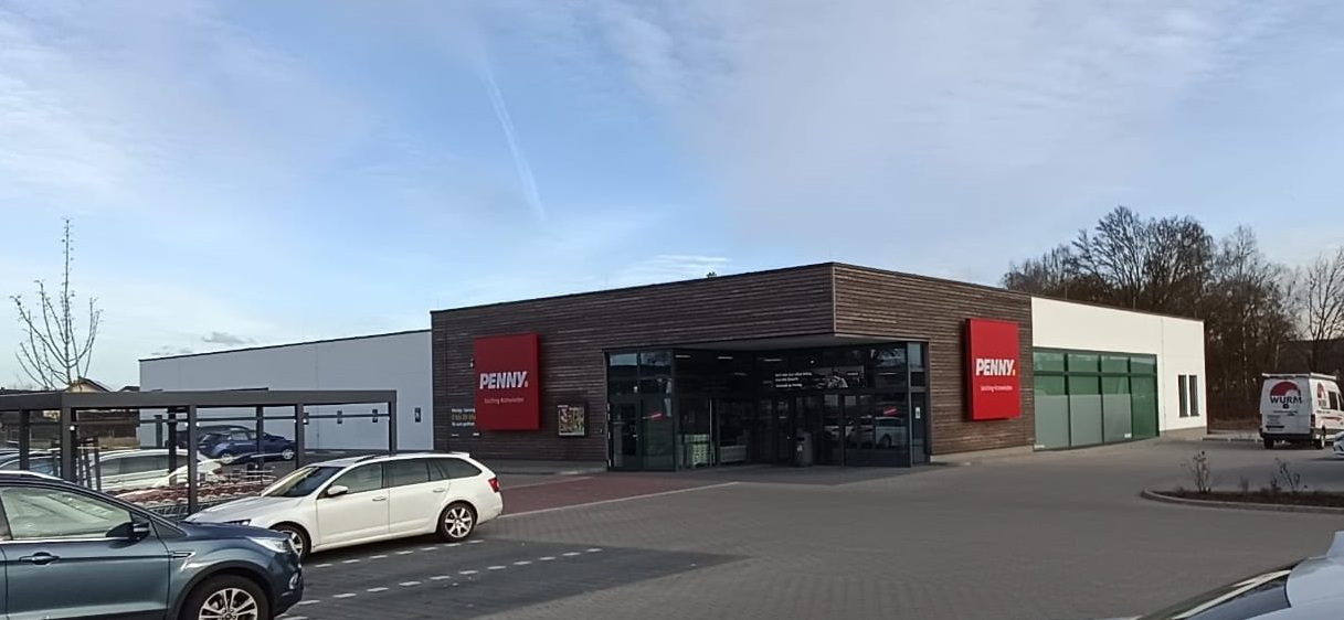 Außenansicht des neu errichteten Penny-Marktes in Loiching mit Parkplatz und Eingangsbereich.