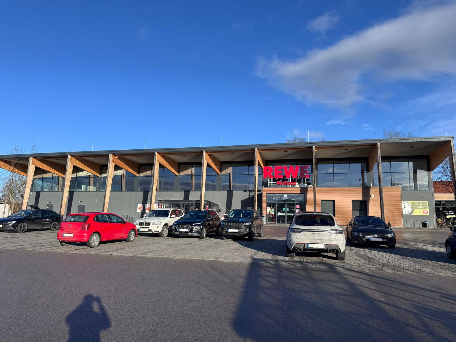 Außenansicht des neu errichteten Rewe-Marktes in Scheyern mit Glas- und Holzfassade.