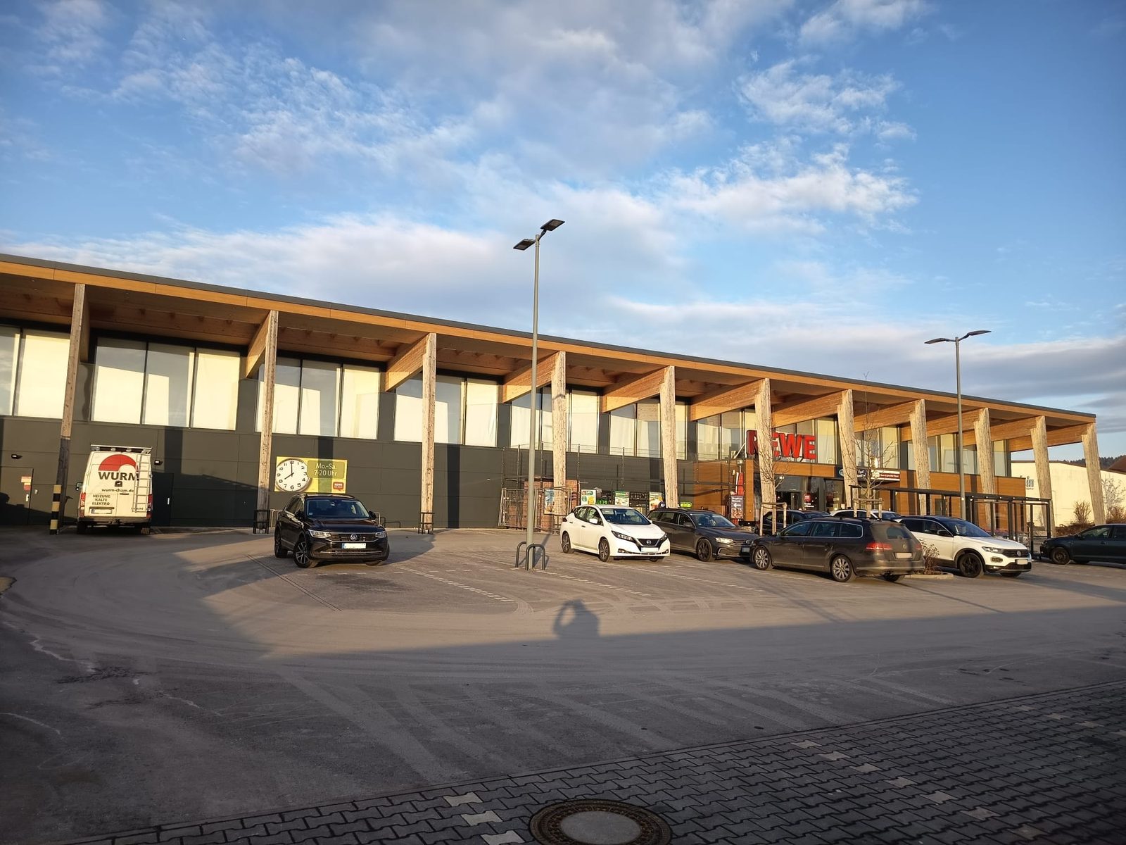 Außenansicht des Neubaus Rewe Untergriesbach in Untergriesbach mit Parkplatz und markanter Holzkonstruktion.